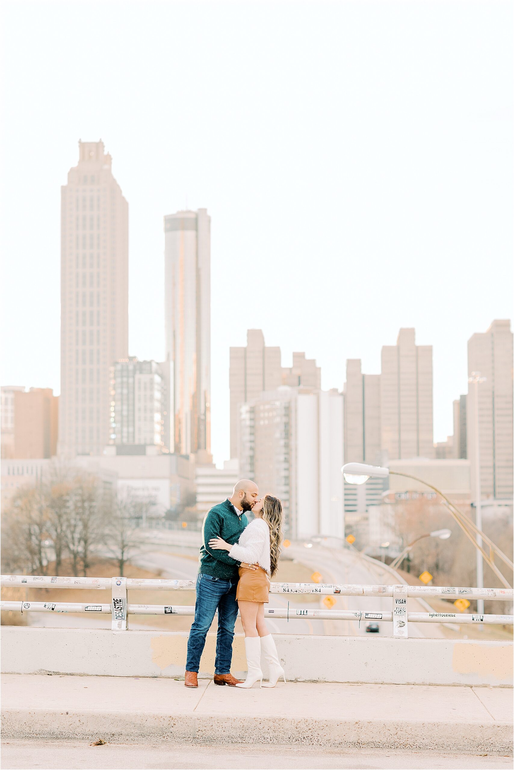 couple walking across a bridge with Atlanta skyline in the background  