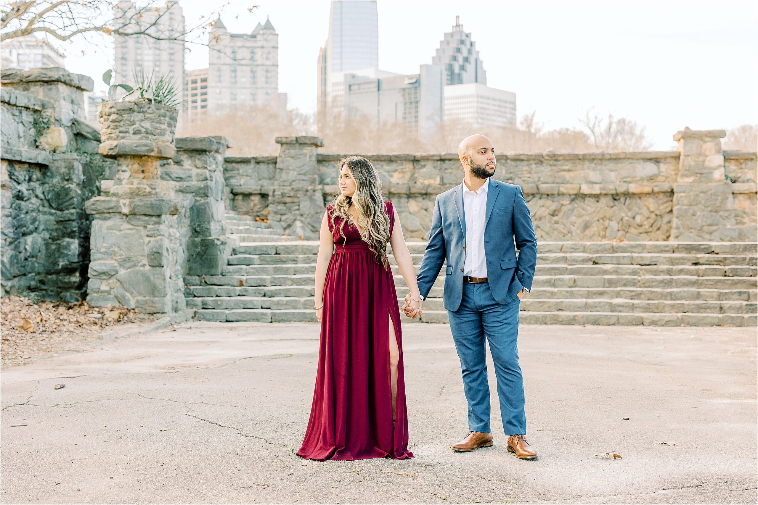 couple in piedmont park, Atlanta GA, wearing a red dress and a blue suit with a stone wall background