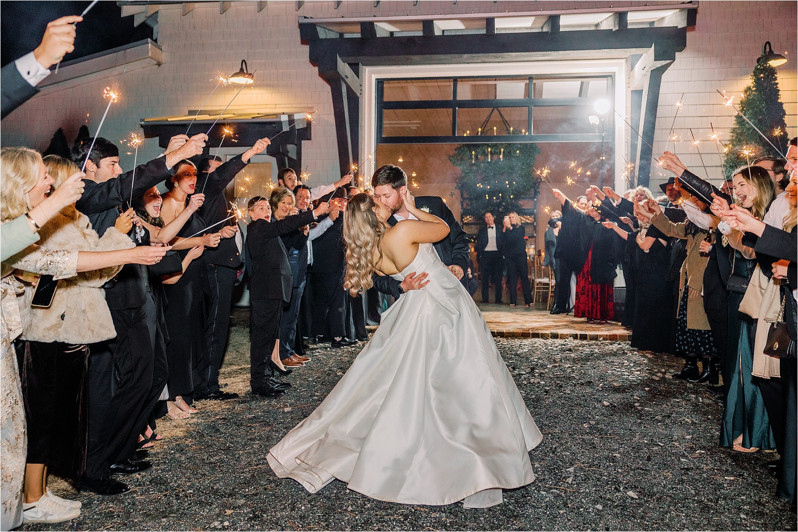 Bride and groom walk through sparkler exit and kiss.  