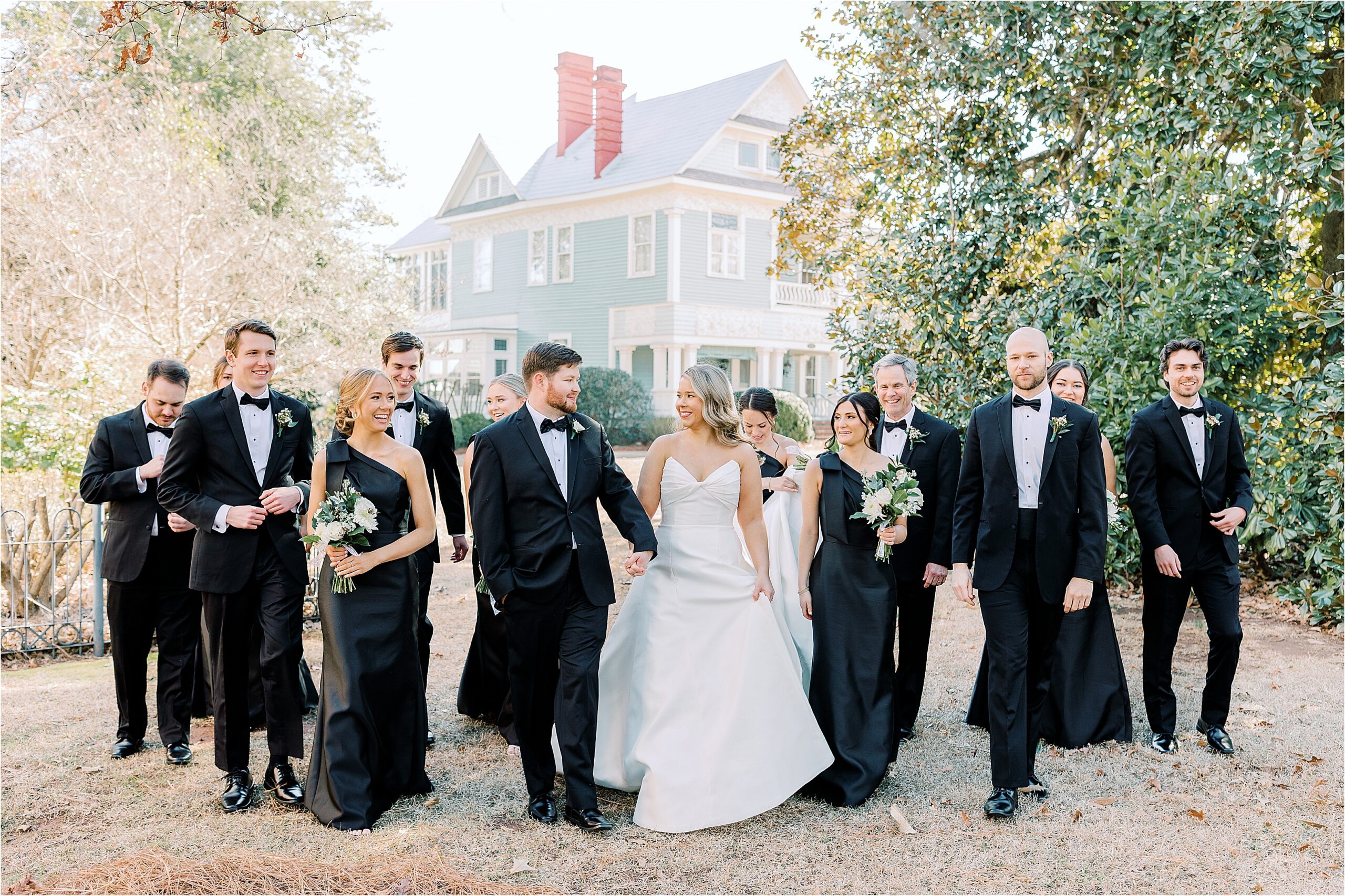 Bride and groom with bridal party dressed in black walking.