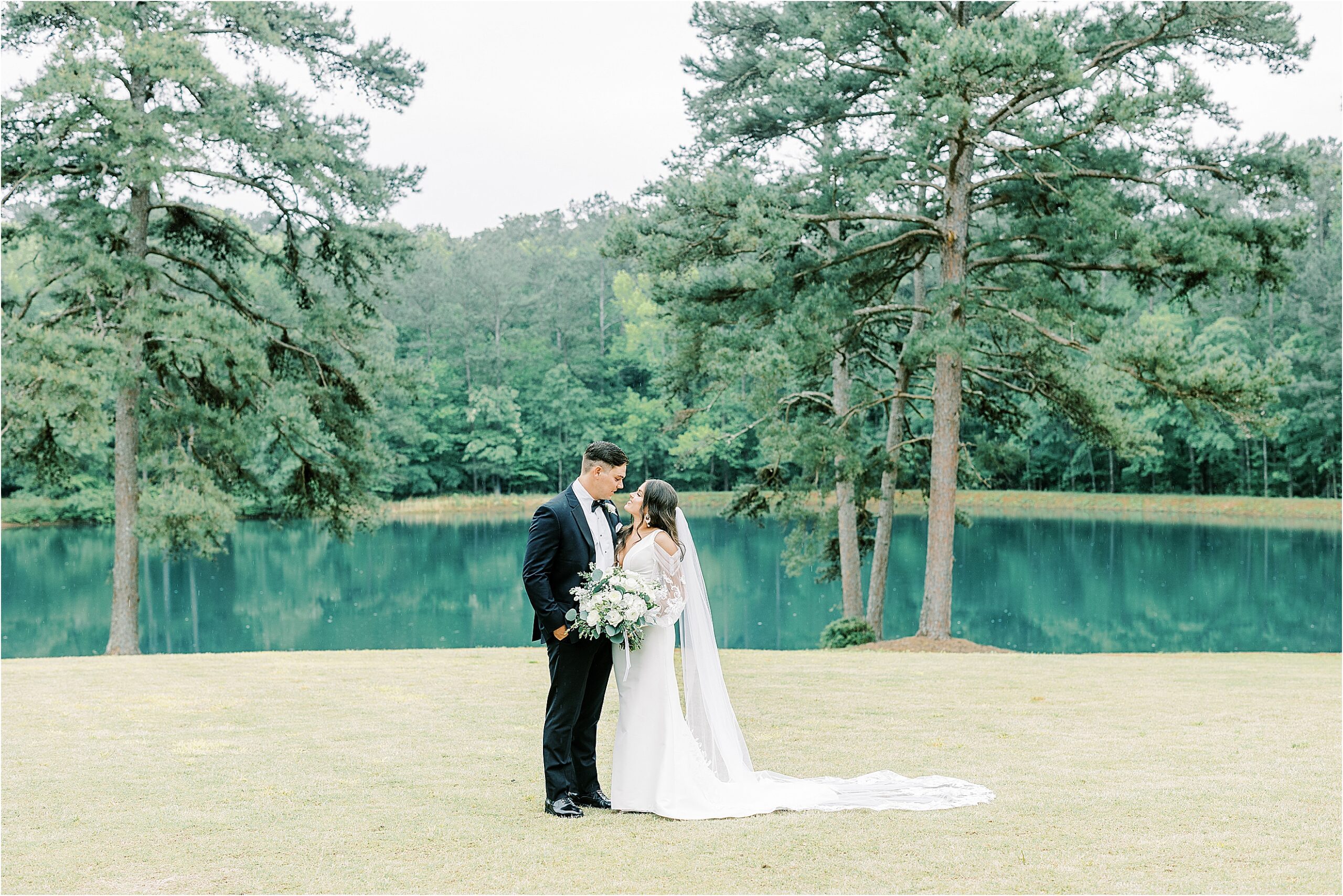 Bride and groom looking at one another, standing in front of pond